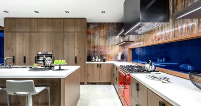 A Kerrisdale kitchen in natural wood cabinetry with a red La Cornue range, white quartz counters and a deep navy backsplash.