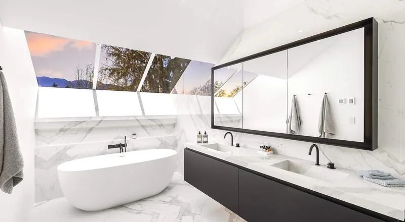 A spa-like Point Grey bathroom: a freestanding tub, dual sinks and full marble surfaces under angled windows looking out to the mountains.
