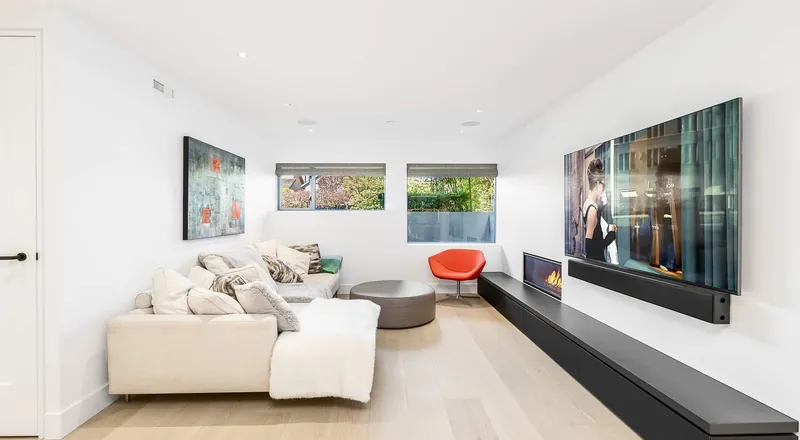 A bright living room with a white sectional, a low fireplace bench and large windows.
