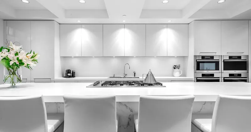 A clean white kitchen island with an integrated cooktop and bar seating.